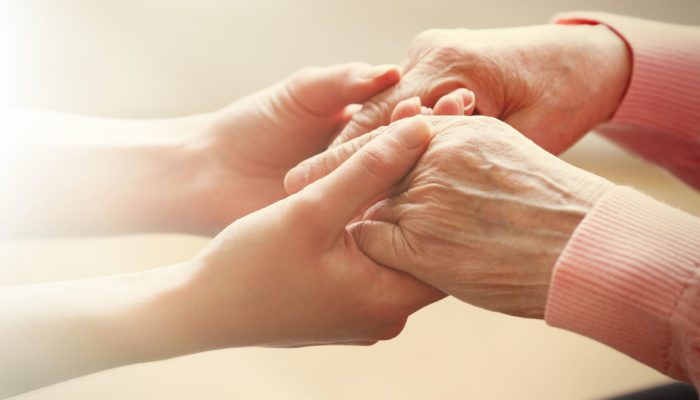 37056637 - old and young holding hands on light background, closeup